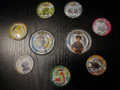 Some normal and Mega Tazos from the first set of Pokémon Metal Tazo