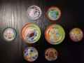 Some normal and Mega Tazos from the second set of Pokémon Metal Tazo